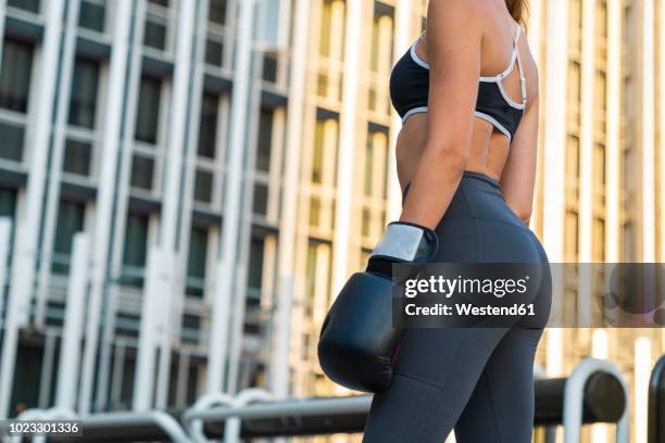 sportive young woman with boxing gloves in the city in front of a high-rise building - ropa de deporte fotografías e imágenes de stock