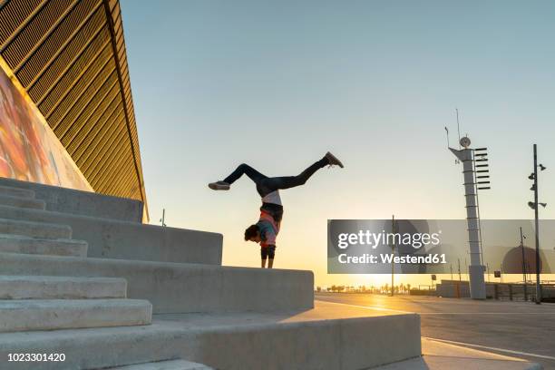 acrobat doing handstand on stairs at sunrise - acrobate photos et images de collection