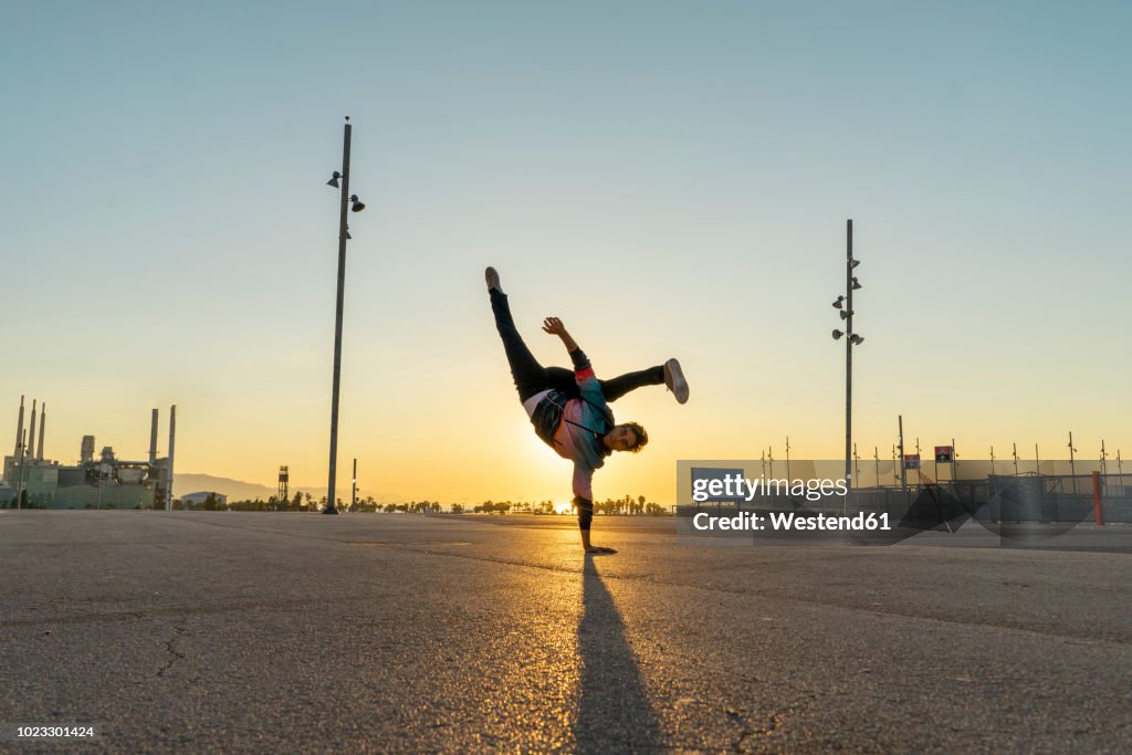 Acrobat doing handstand in the city at sunrise
