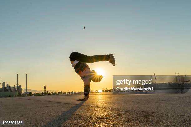 acrobat doing handstand in the city at sunrise - sunrise city stock-fotos und bilder