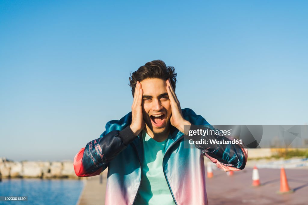 Surprised man screaming for joy with hands on head