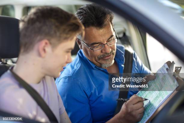learner driver with instructor in car looking at test script - boy in briefs photos et images de collection