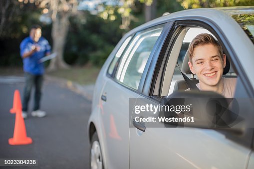 Smiling learner driver learning to drive looking at wing mirror of a car Smiling learner driver learning to drive looking at wing mirror of a car