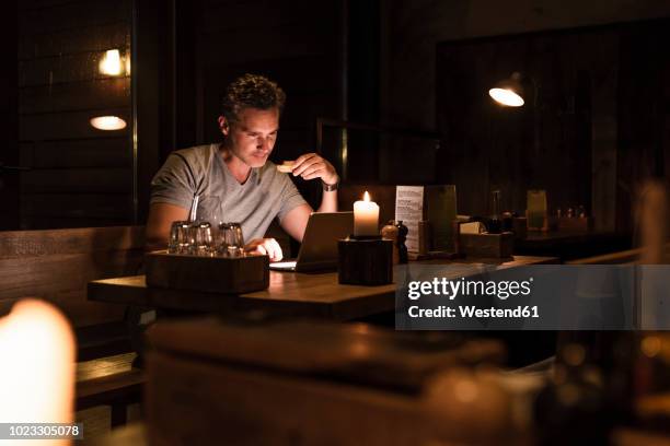 man having dinner looking at laptop - candle light foto e immagini stock