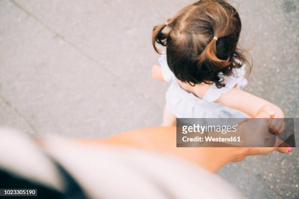 toddler girl walking holding mother's hand - baby girls stockfoto's en -beelden