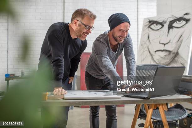 smiling artist using laptop with man in studio - curator fotografías e imágenes de stock