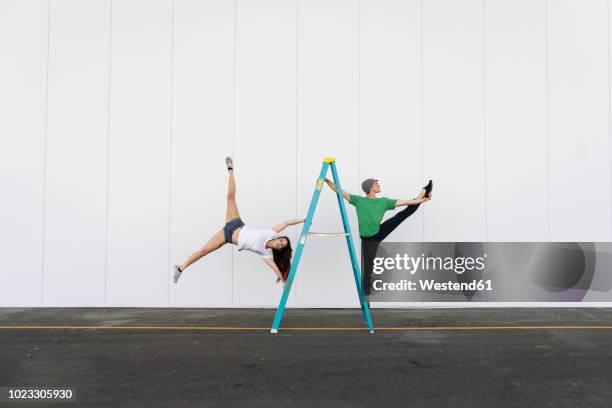 two acrobats doing tricks on a ladder - zirkus stock-fotos und bilder