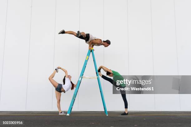 three acrobats doing tricks on a ladder - acrobate photos et images de collection