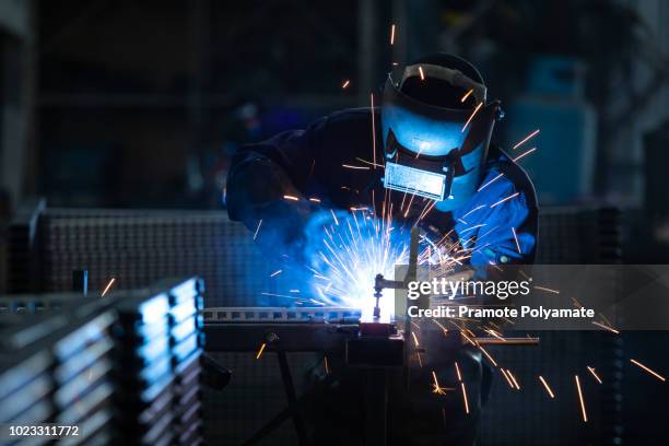 workers wearing industrial uniforms and welded iron mask at steel welding plants, industrial safety first concept. - lasser stockfoto's en -beelden
