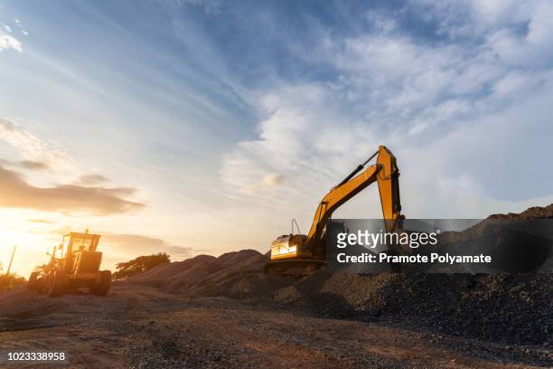 backhoe used in construction, big excavator on new construction site, in the background the blue sky and sun. - excavator imagens e fotografias de stock