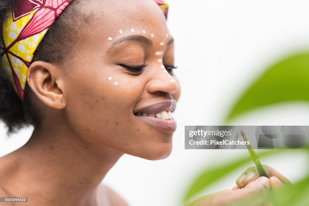 Close up profile young African woman's face painting traditional make up