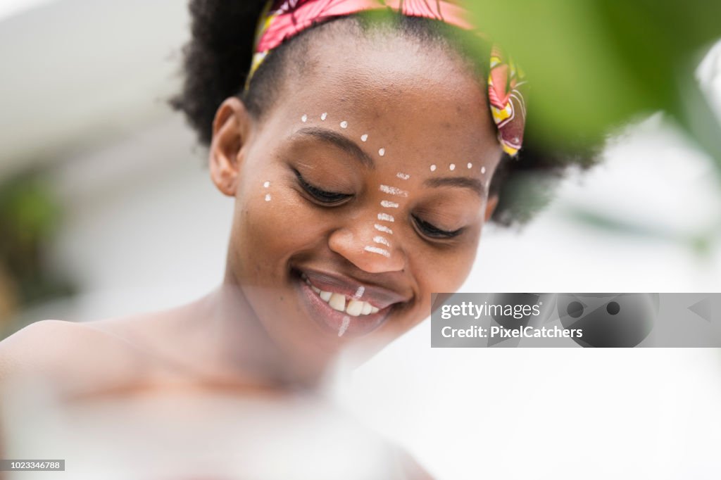 Low angle candid portrait young African woman with traditional face paint