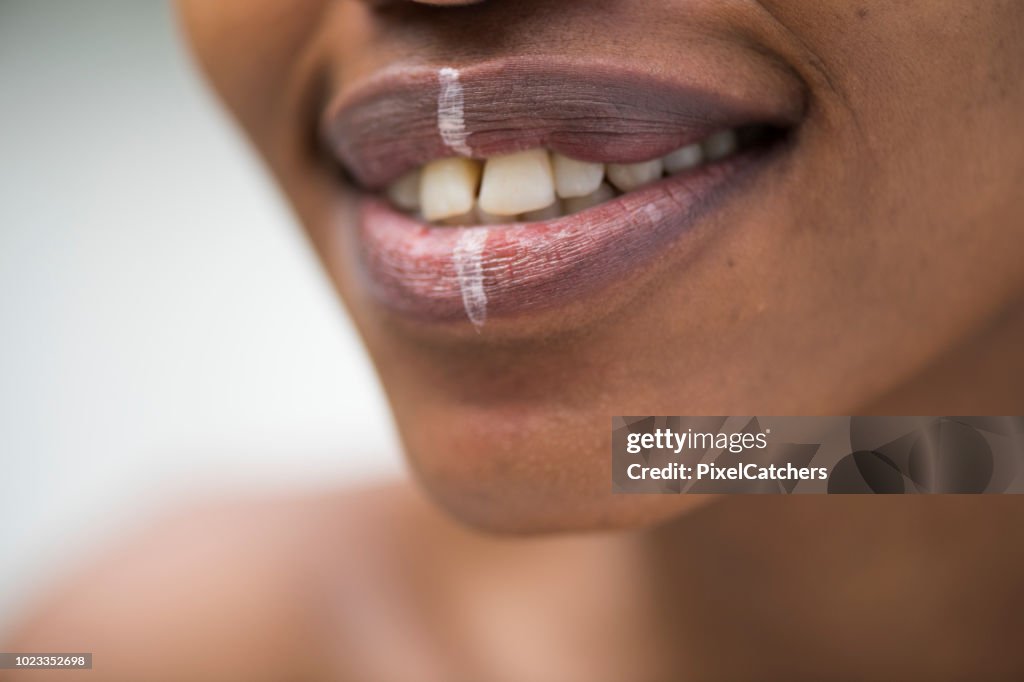 Extreme close up young African woman's mouth with traditional face paint