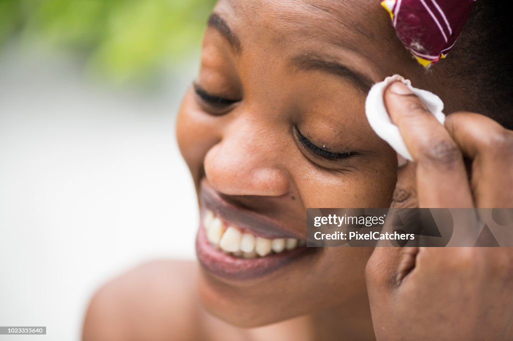 Close up candid moment young African woman cleans her face eyes closed