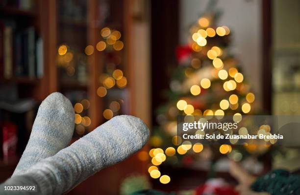 close-up of relaxing feet at home with bokeh of christmas lights behind - personne non reconnaissable photos et images de collection