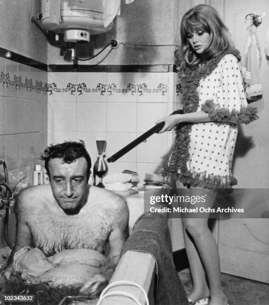 Olimpia Segura points a shotgun at Juan Bautista forcing him to dye himself blue in a bathtub in a scene from the movie "The Bobo" which was released...