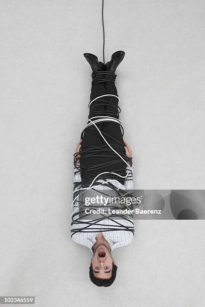 businessman tied up with computer cable, elevated view - amarrado fotografías e imágenes de stock