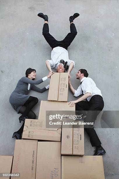 three business people on cardboard boxes, man doing handstand, smiling, portrait, elevated view - businesswoman handstand stock-fotos und bilder