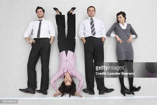 four business people side by side, woman doing handstand, portrait, elevated view - businesswoman handstand stock-fotos und bilder