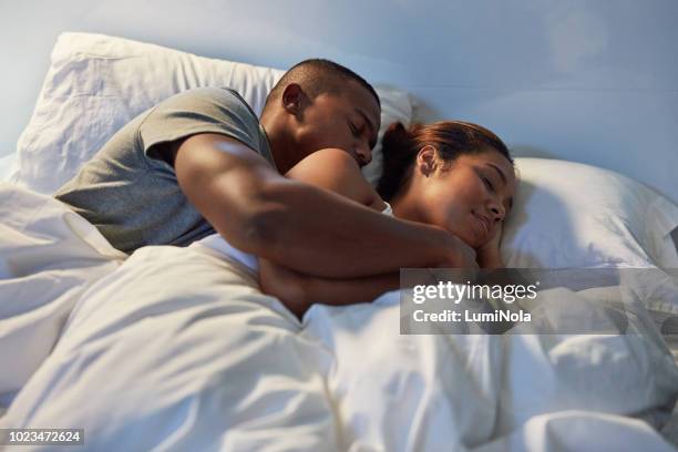 it's great having someone to hold at night - romantic young couple sleeping in bed stock pictures, royalty-free photos & images