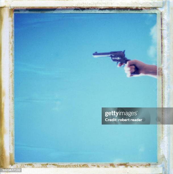 polaroid photograph of hand holding toy gun - arma de brinquedo imagens e fotografias de stock