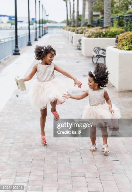 sisters wearing dresses, playing in rain puddles - kids tiara stock pictures, royalty-free photos & images