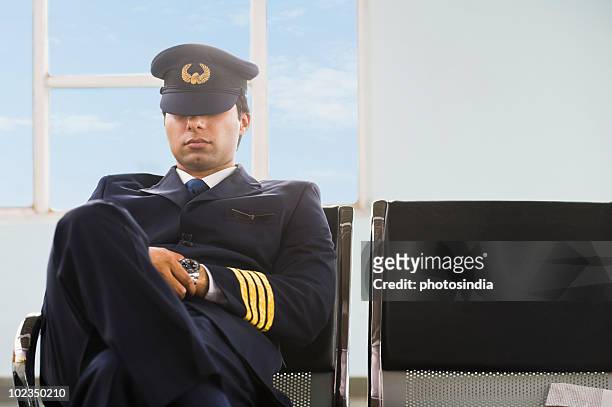 pilot napping on the bench at an airport - captains day stock-fotos und bilder