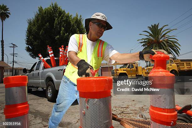 Ernest Beas, an employee of ICE Engineering, picks up traffic control posts after completing a speed bump construction project that was contracted...