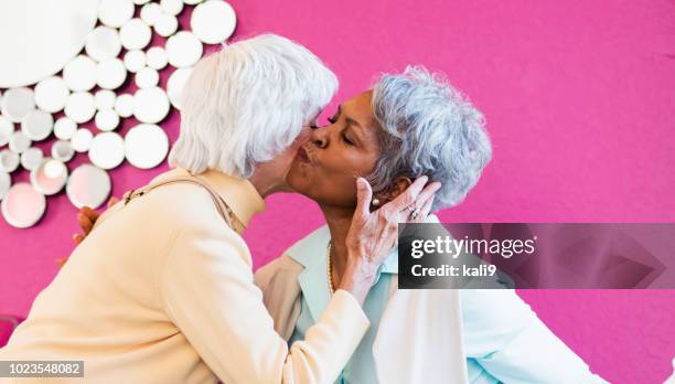 two senior women meeting in coffee shop - cheek kiss stock pictures, royalty-free photos & images