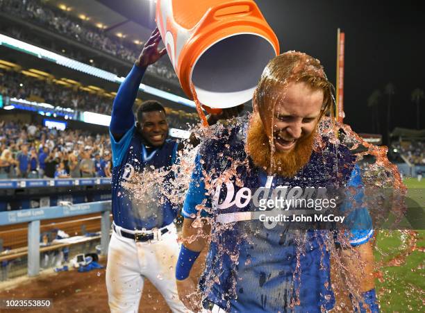 Justin Turner of the Los Angeles Dodgers is soaked with sports drink by Yasiel Puig after the RBI single that scored Chris Taylor in the 12th inning...