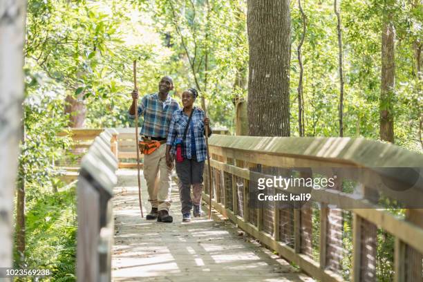 senior african-american couple hiking, on footbridge - florida bridge stock pictures, royalty-free photos & images