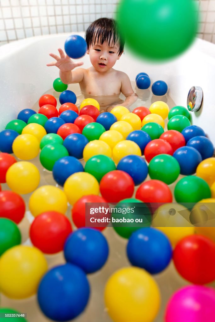 Baby playing with color balls in the bathtub