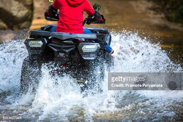 the girl driving an atv through the river spree. - forrest wheeler fotografías e imágenes de stock
