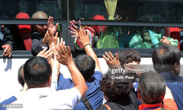 North Koreans on a bus hold hands of their South Korean relatives to bid farewell after the separated family reunion meeting at the Mount Kumgang...