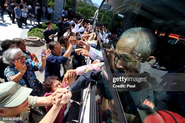 North Koreans on a bus hold hands of their South Korean relatives to bid farewell after the separated family reunion meeting at the Mount Kumgang...