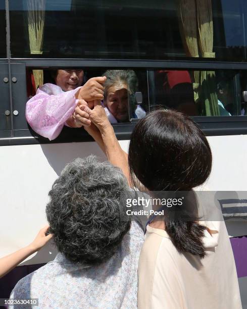 North Koreans on a bus hold hands of their South Korean relatives to bid farewell after the separated family reunion meeting at the Mount Kumgang...