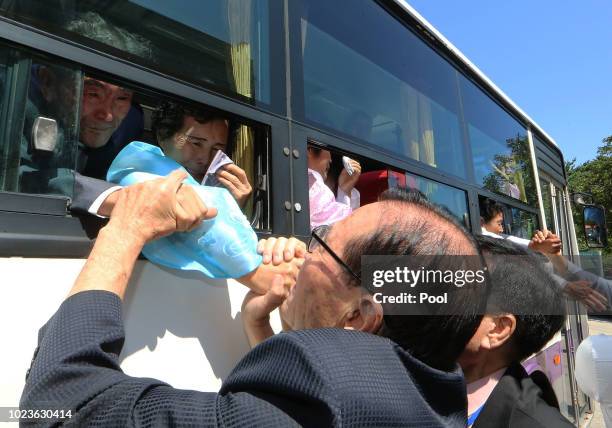 North Koreans on a bus hold hands of their South Korean relatives to bid farewell after the separated family reunion meeting at the Mount Kumgang...