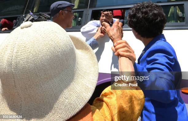 North Koreans on a bus hold hands of their South Korean relatives to bid farewell after the separated family reunion meeting at the Mount Kumgang...