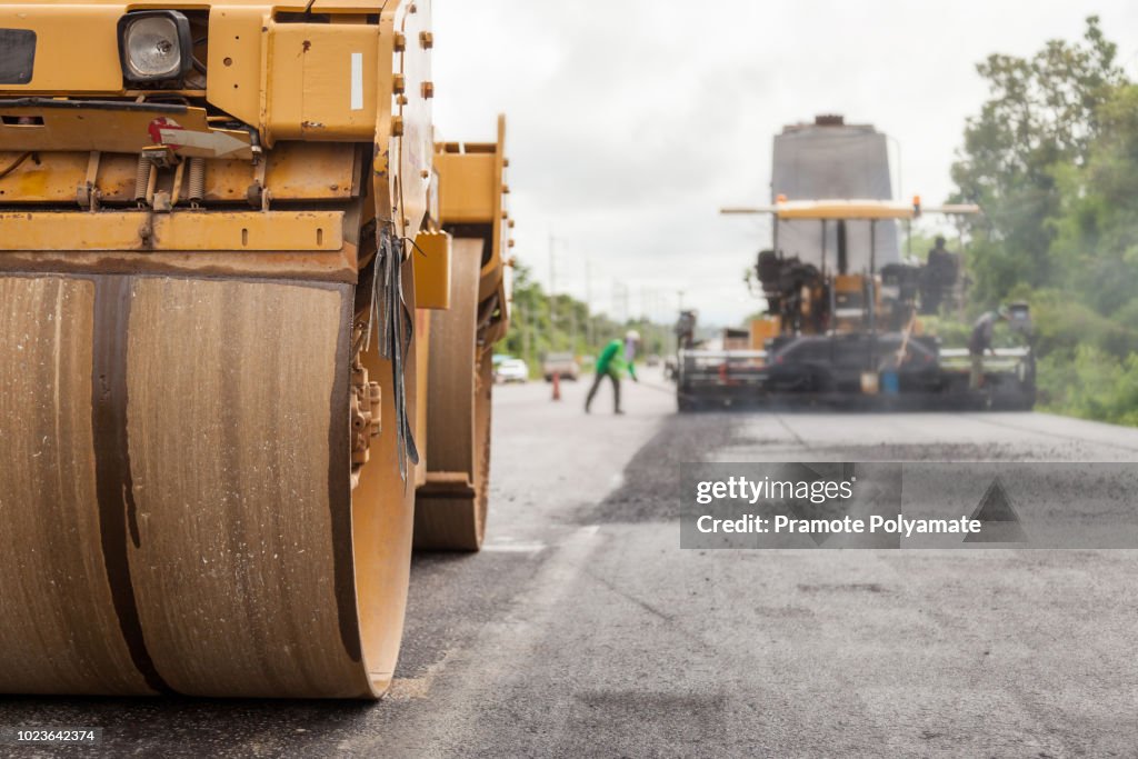 Road construction works with roller compactor machine and asphalt finisher.