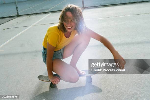 girl smiling and riding barefoot on skateboard - leisure equipment stock-fotos und bilder