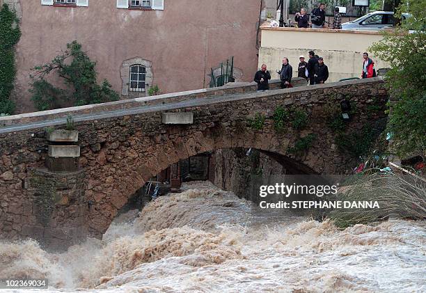 People look at Nartuby river in flood in the aftermath of flooding in a western district of the French south eastern city of Trans-en-Provence on...