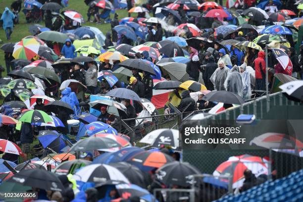 Crowds huddle under umbrellas as the start of the MotoGP race is delayed due to rain during the motorcycling British Grand Prix at Silverstone...