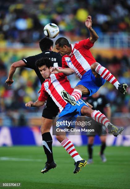 Cristian Riveros and Paulo Da Silva of Paraguay jump into Rory Fallon of New Zealand during the 2010 FIFA World Cup South Africa Group F match...