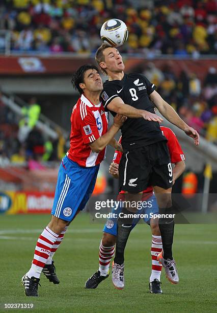 Julio Cesar Caceres of Paraguay and Shane Smeltz of New Zealand jump for the ball during the 2010 FIFA World Cup South Africa Group F match between...