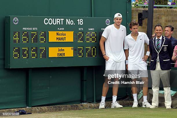 John Isner of USA poses after winning on the third day of his first round match against Nicolas Mahut of France with Chair Umpire Mohamed Lahyani on...