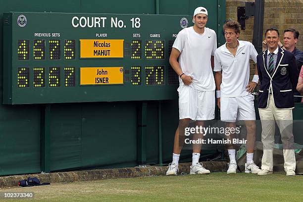 John Isner of USA poses after winning on the third day of his first round match against Nicolas Mahut of France with Chair Umpire Mohamed Lahyani on...