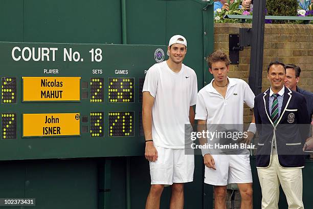 John Isner of USA poses after winning on the third day of his first round match against Nicolas Mahut of France with Chair Umpire Mohamed Lahyani on...