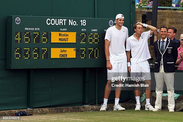 John Isner of USA poses after winning on the third day of his first round match against Nicolas Mahut of France with Chair Umpire Mohamed Lahyani on...