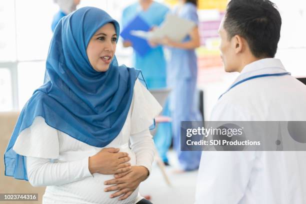 pregnant woman talks seriously with ob/gyn - pregnant muslim stock pictures, royalty-free photos & images