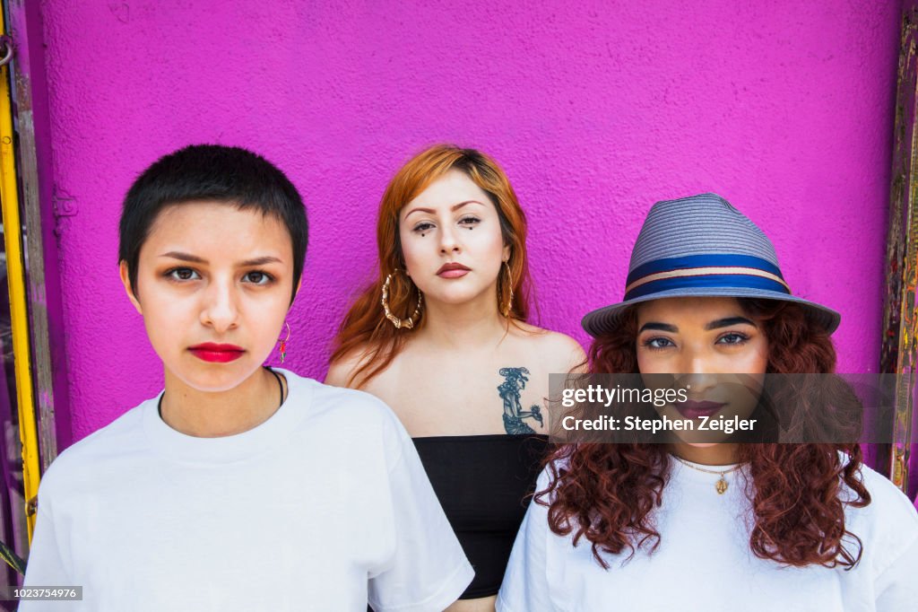 Three young women in front of pink background